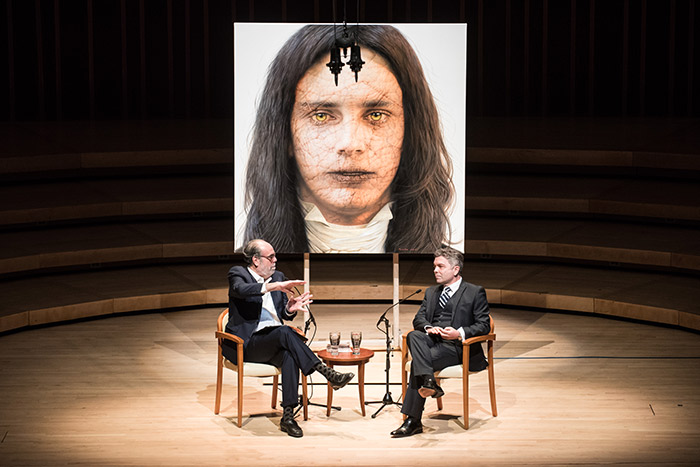 Ross Rossin and Bill Nigut sit in chairs on the stage to discuss Rossin's vision for the creation.