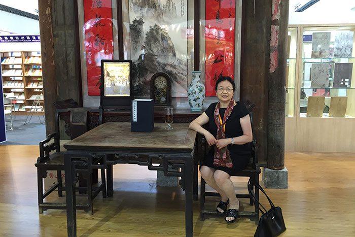 Chinese Studies librarian Guo-hua Wang sits at the entrance to the booth of her native province of Anhui, which is decorated like the living room of a home, at the Beijing International Book Fair last year.
