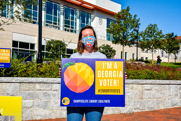 A student wearing a mask holds up a sign that says: "I'm a Georgia voter"