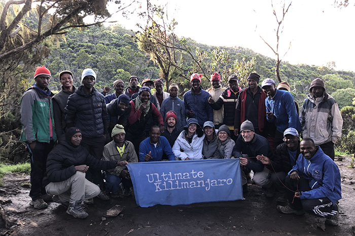 A large group holds a banner that reads 'Ultimate Kilimanjaro'