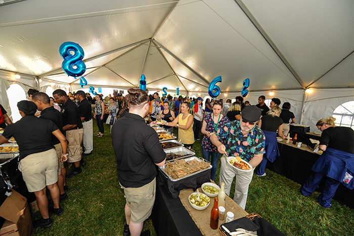 Emory staff members gather under a tent to eat a catered lunch