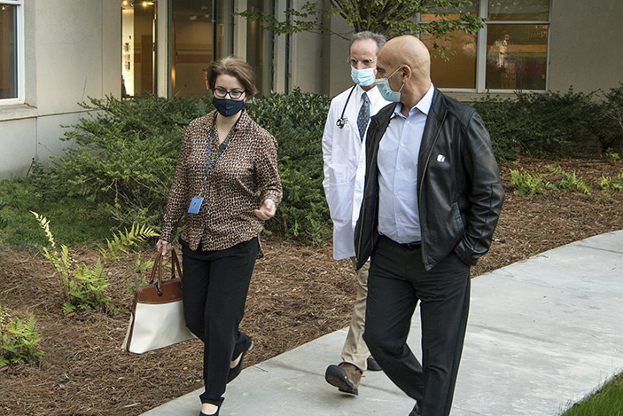 Moncef Slaoui walks with Nadine Rouphael and Evan Anderson outside the Emory Children’s Center