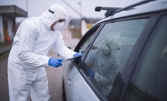 Man in protective suit standing outside a car