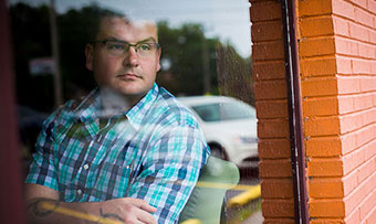 Michael Yandell reflectively looks through a window