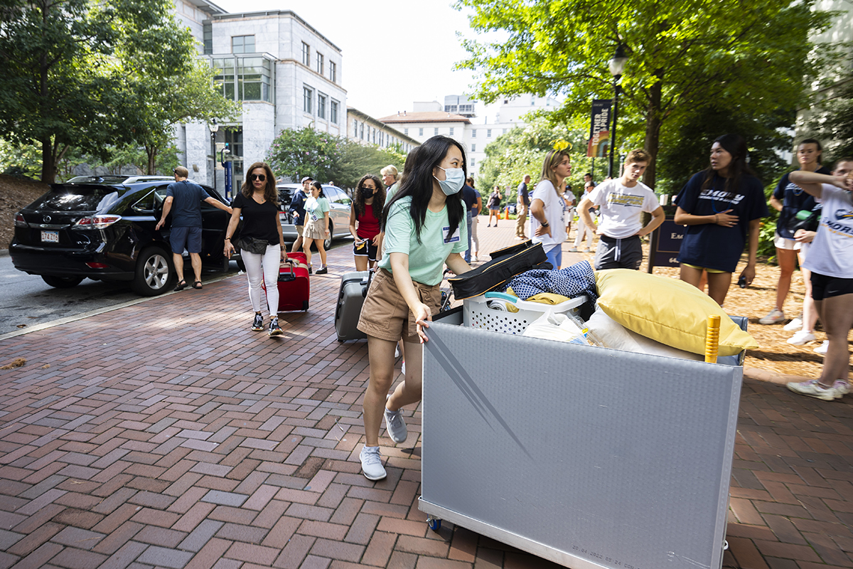 Photo of students moving their belongings from parked cars to residence halls.