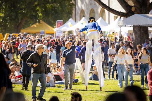Man on stilts high-fives a person in an Emory shirt