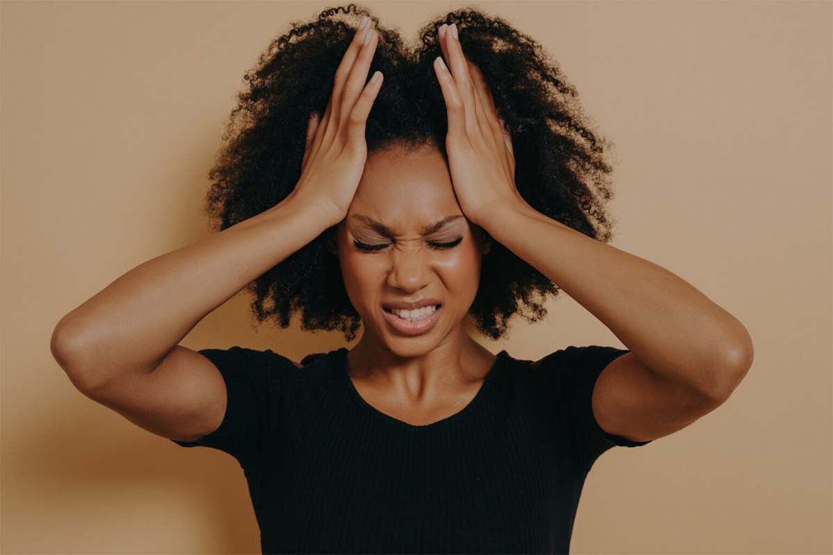 photo of woman holding her head and making a face as if she is in pain