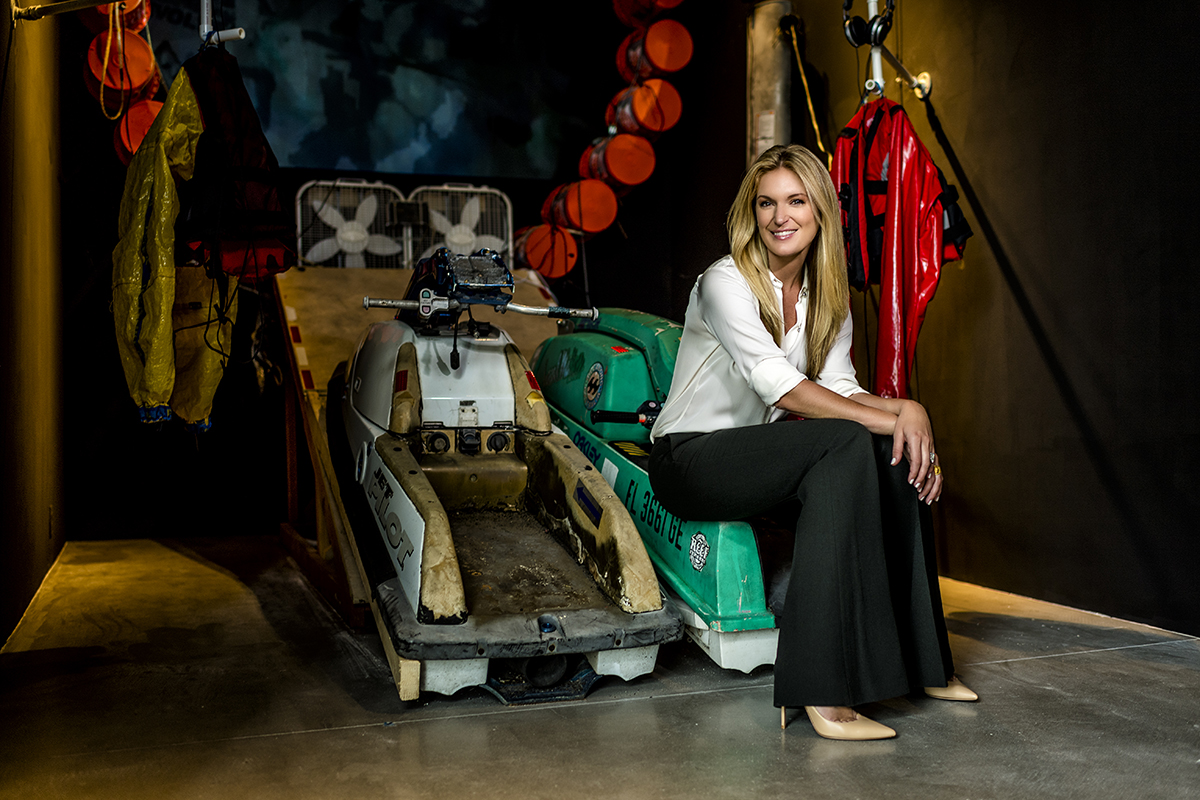 Sarah Arison sits in front of an art exhibit 