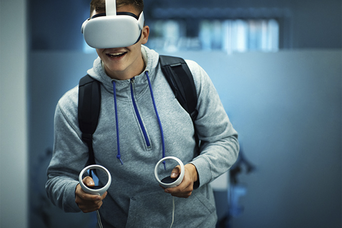 a teenage boy wearing a gray sweatshirt with a virtual reality headset and controls