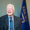 President Jimmy Carter seated in a chair laughing