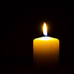 lit candle against black background