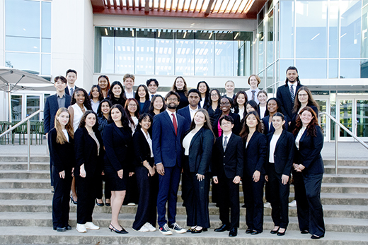 group of college students wearing business suits standing on stairs in front of building