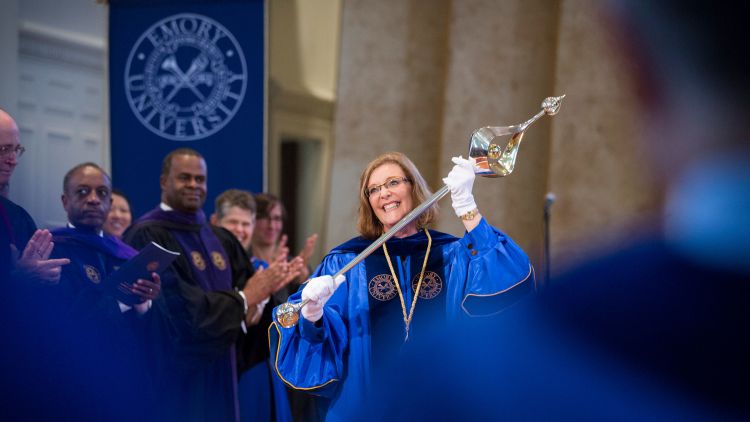 Emory President Claire E. Sterk holds aloft the university mace during her inauguration as university's 20th president.