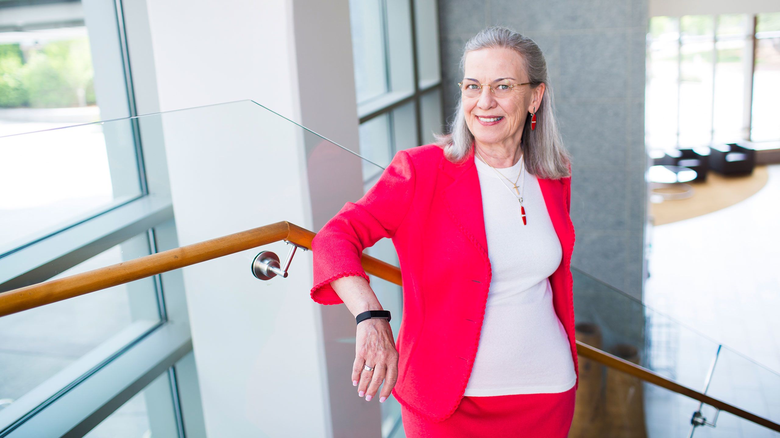 Professor Carol Hogue stands on a staircase in front of windows.