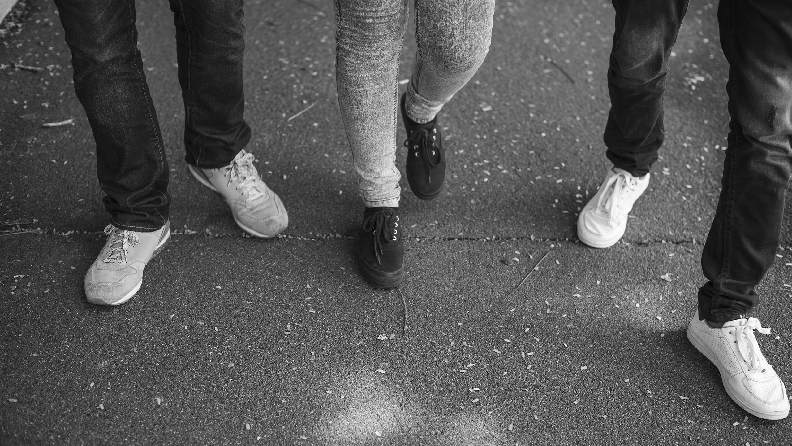 Teens hanging out on the street in jeans and sneakers.