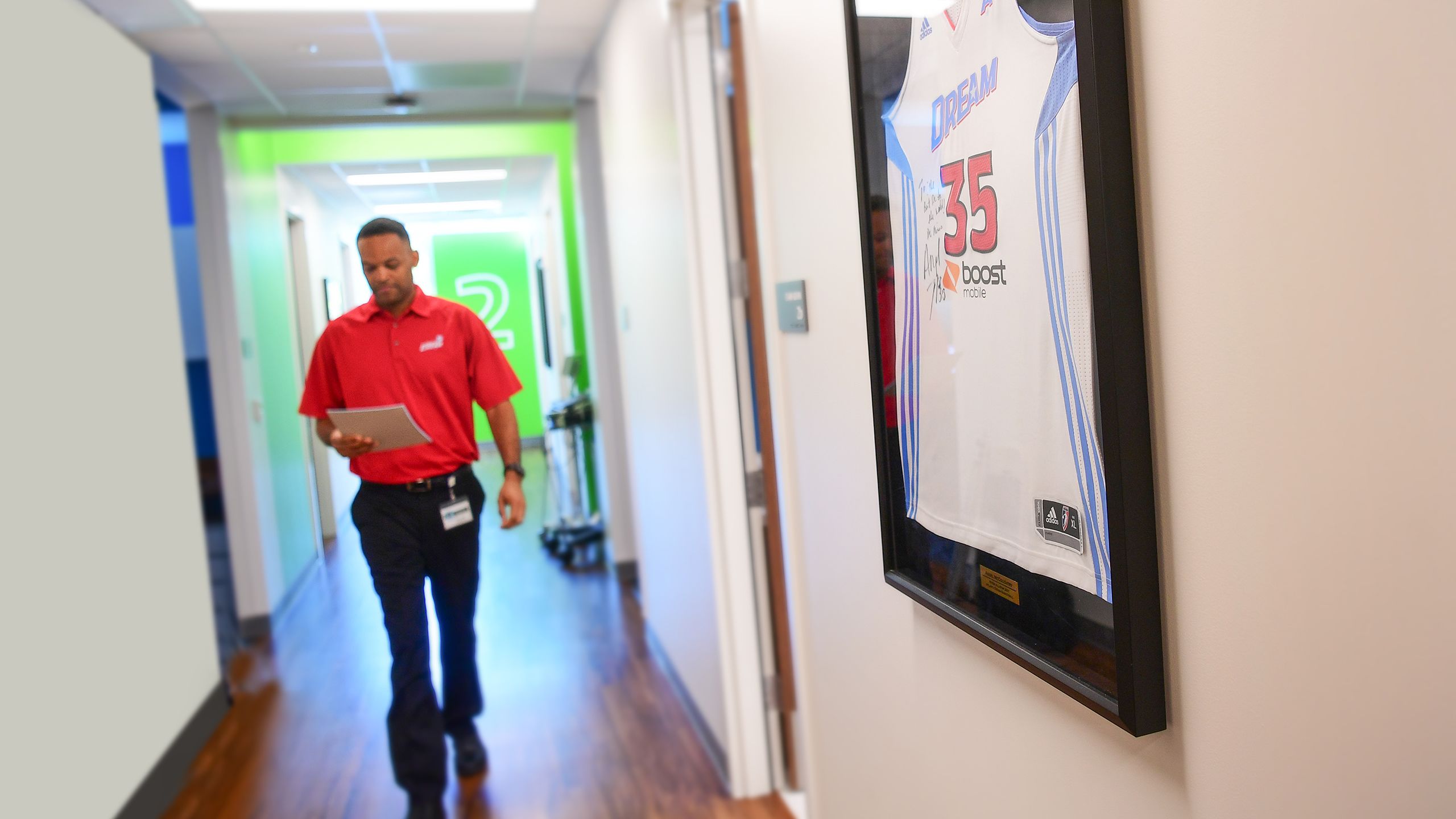 Sports Medicine physician Brandon Mines walking between one appointment and another in the hallway lined with sports memorabilia from grateful patients. 