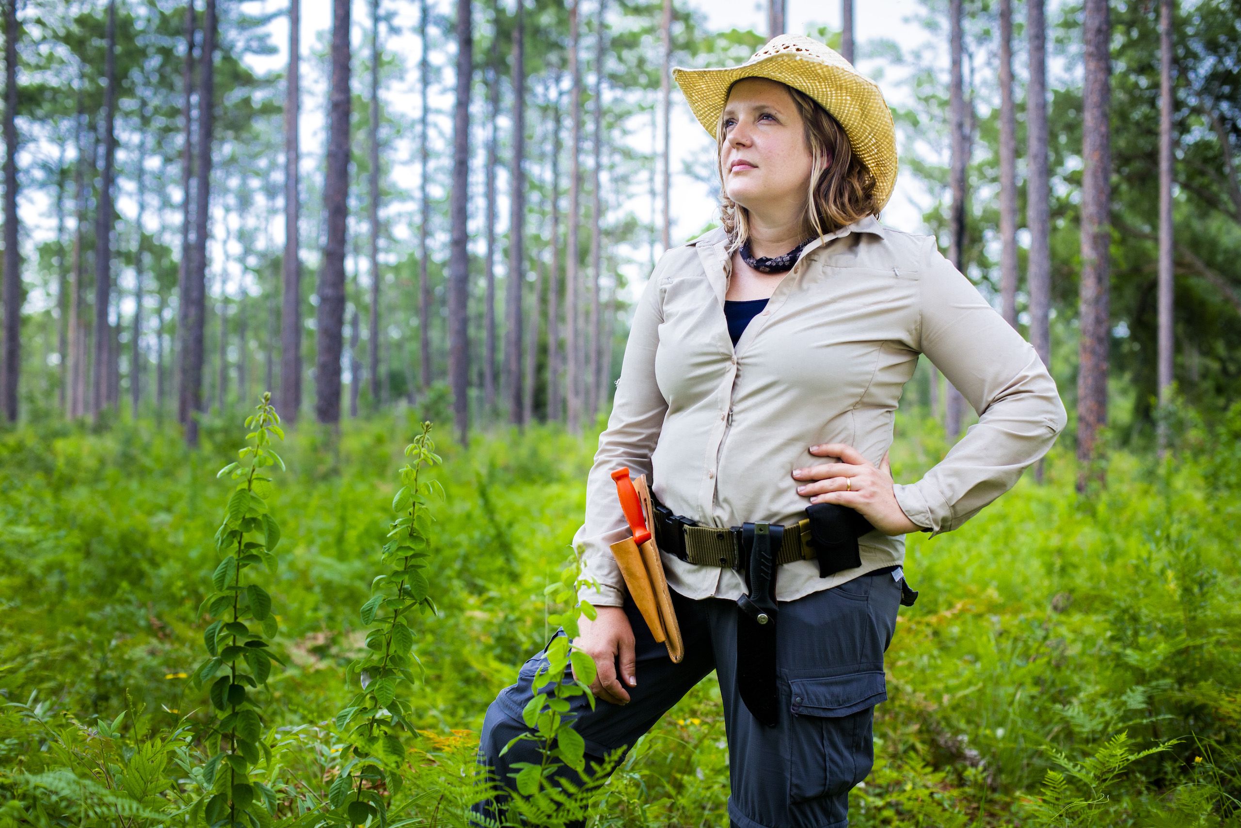 Cassandra Quave stands in a forest clearing looking into the distance.