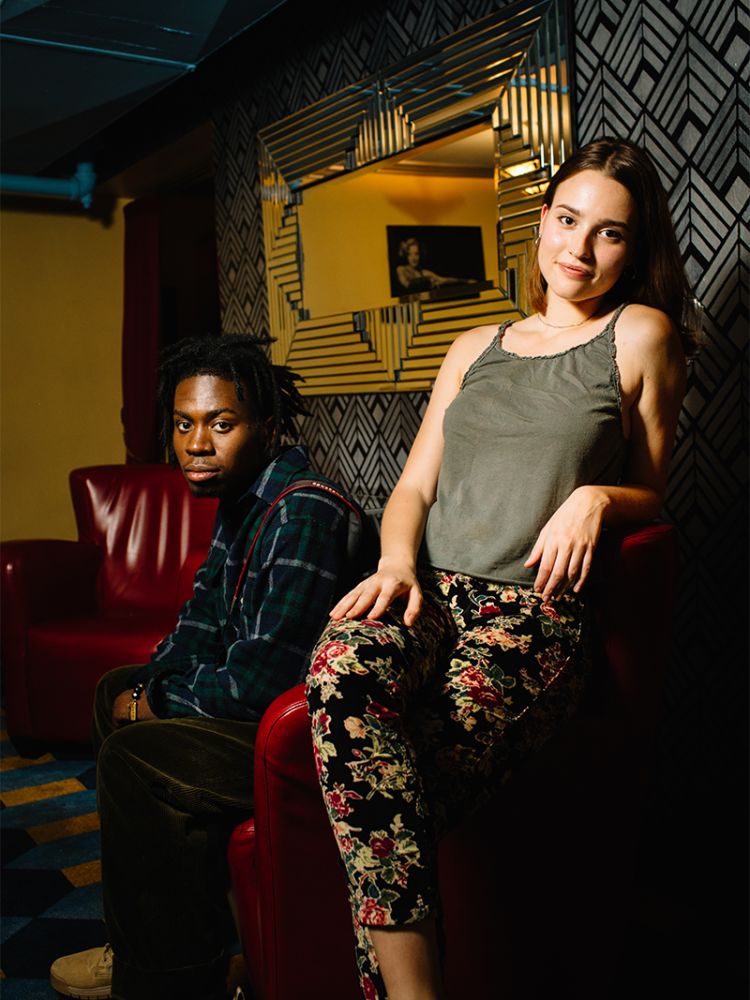 Jard Lerebours and Michelle Baltrusitis sit on red leather chairs in the lounge of the Plaza Theatre in Atlanta.