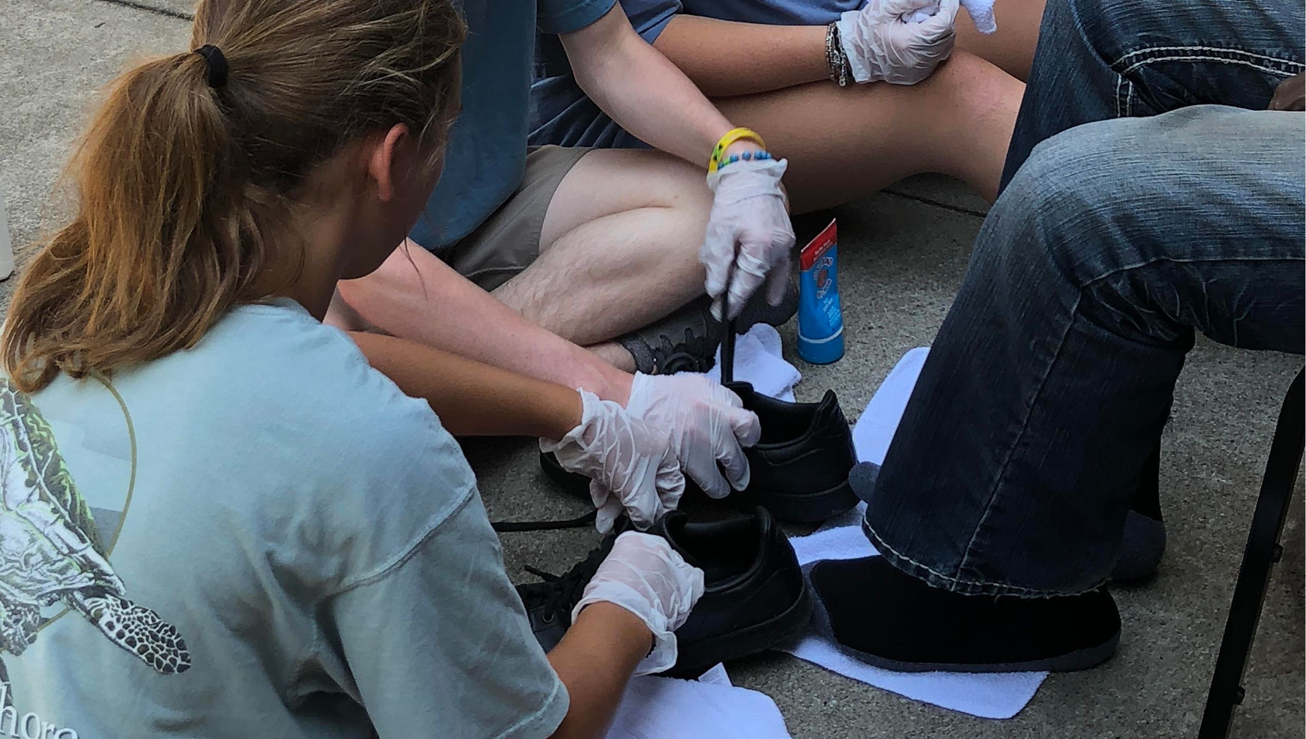 Volunteers wearing gloves untie the shoes of a man at the Gateway Center.