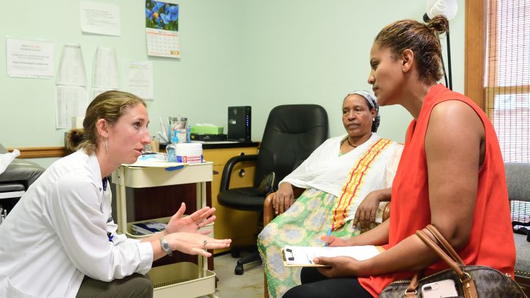 An Emory medical student speaks with patients at Clarkston clinic in an exam room.