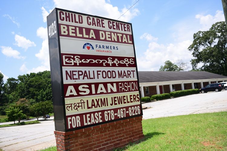 A sign shows a diversity of ethnic businesses in different languages in Clarkston.