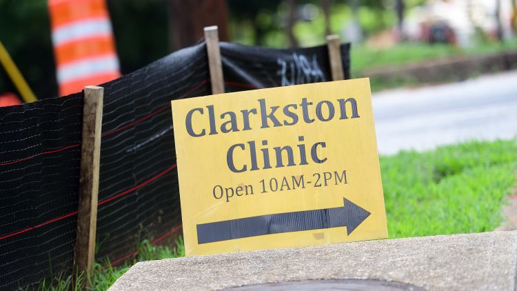 A sign for the Clarkston clinic shows that it is open. 