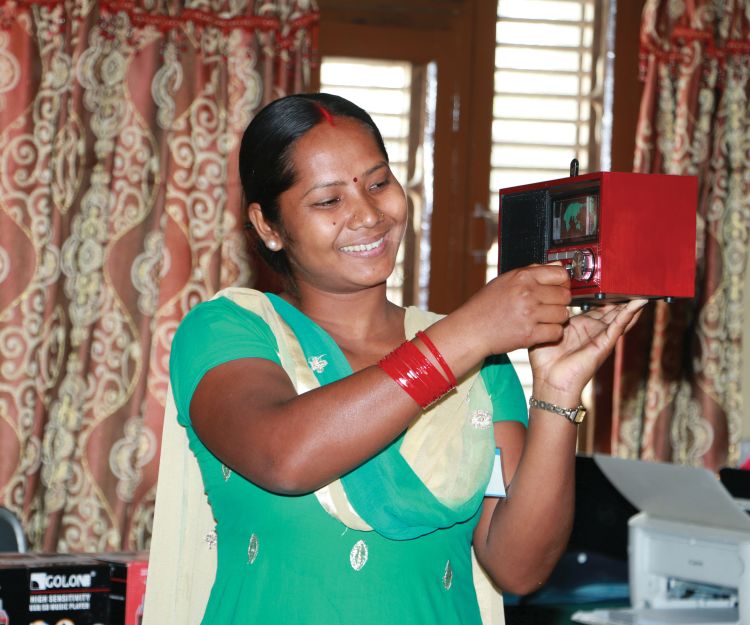A woman in traditional Nepali garb holds a radio.