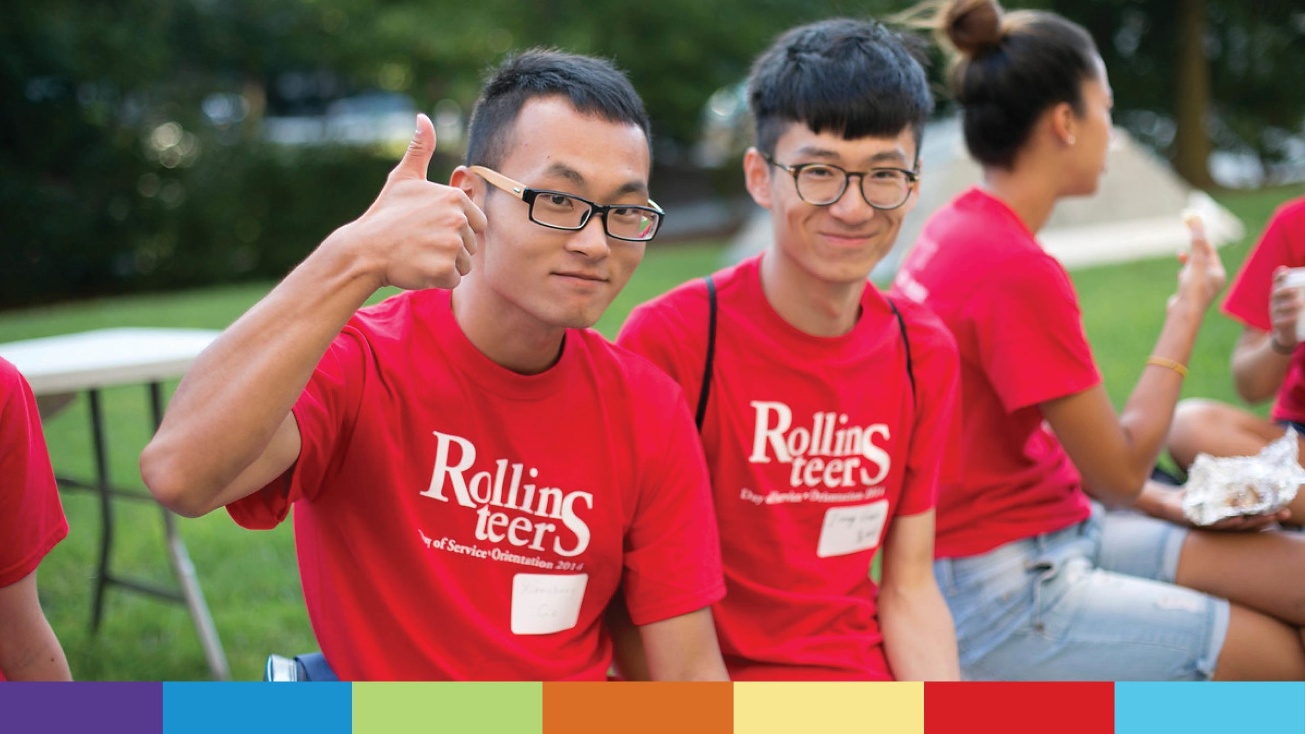 Two young men in red Rollins-teer shirts smile at camera