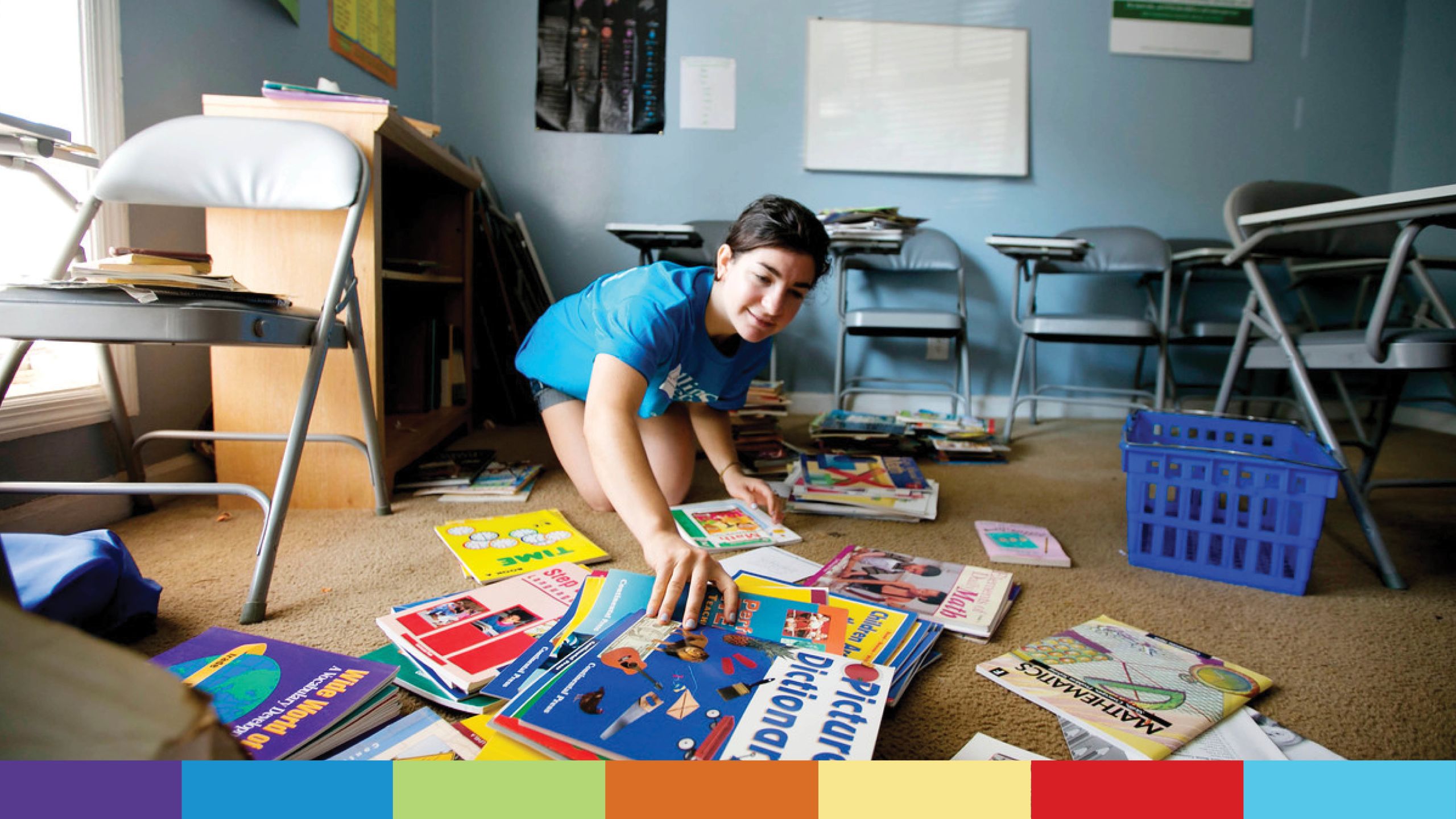 A young woman in a blue T-shirt organizes children's books