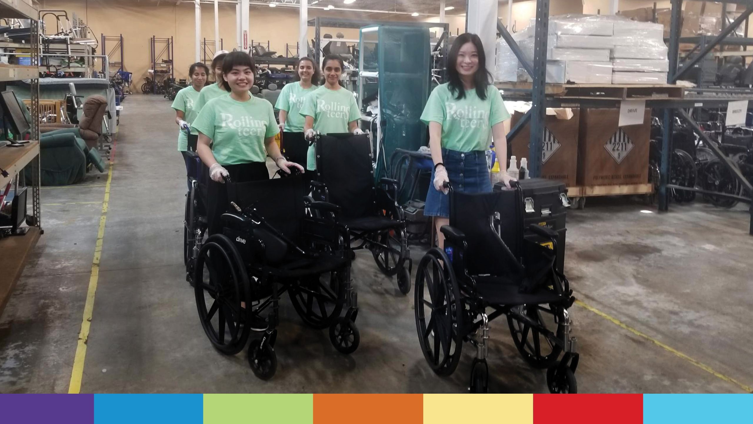A group of volunteers in green T-shirts push wheel chairs