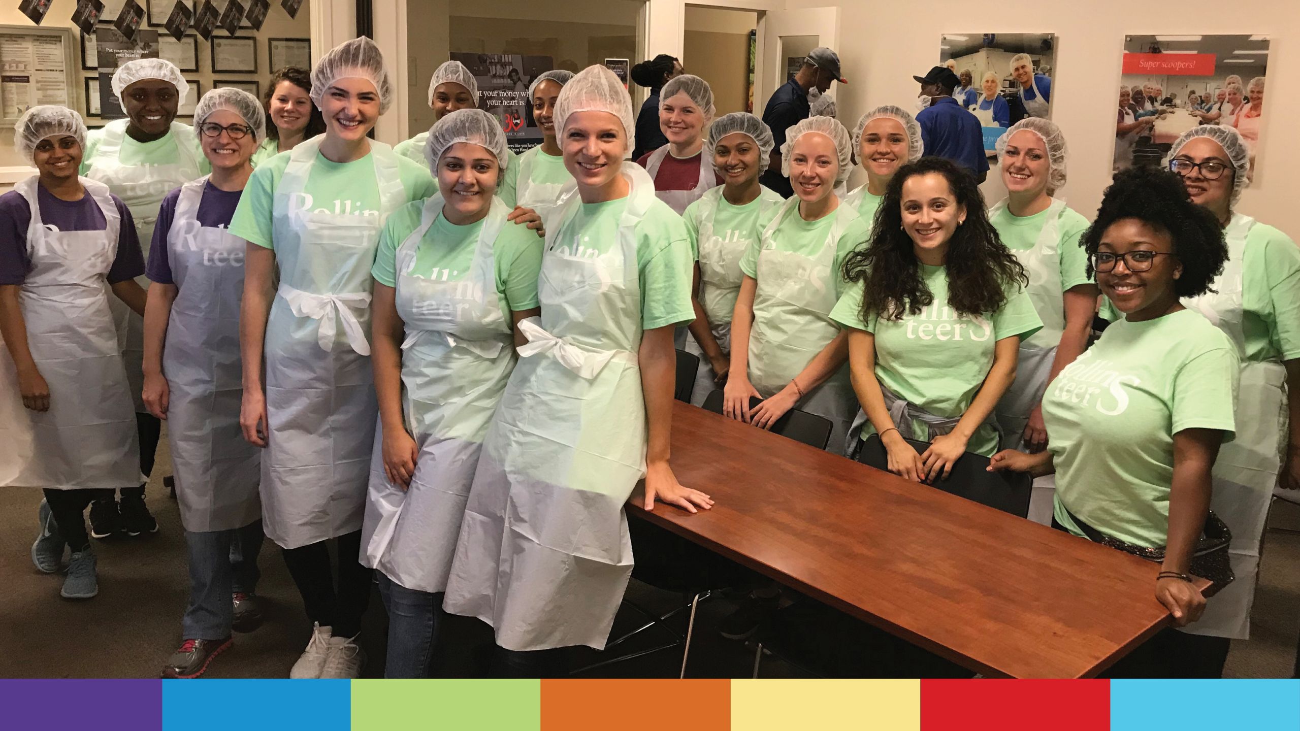 A group of voluneers in hair nets and aprons get ready to prepare food
