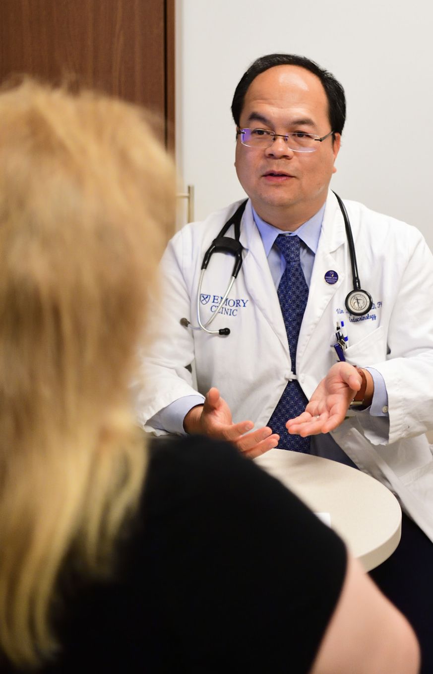 Dr. Vin Tangpricha in a white coat talks to a patient.