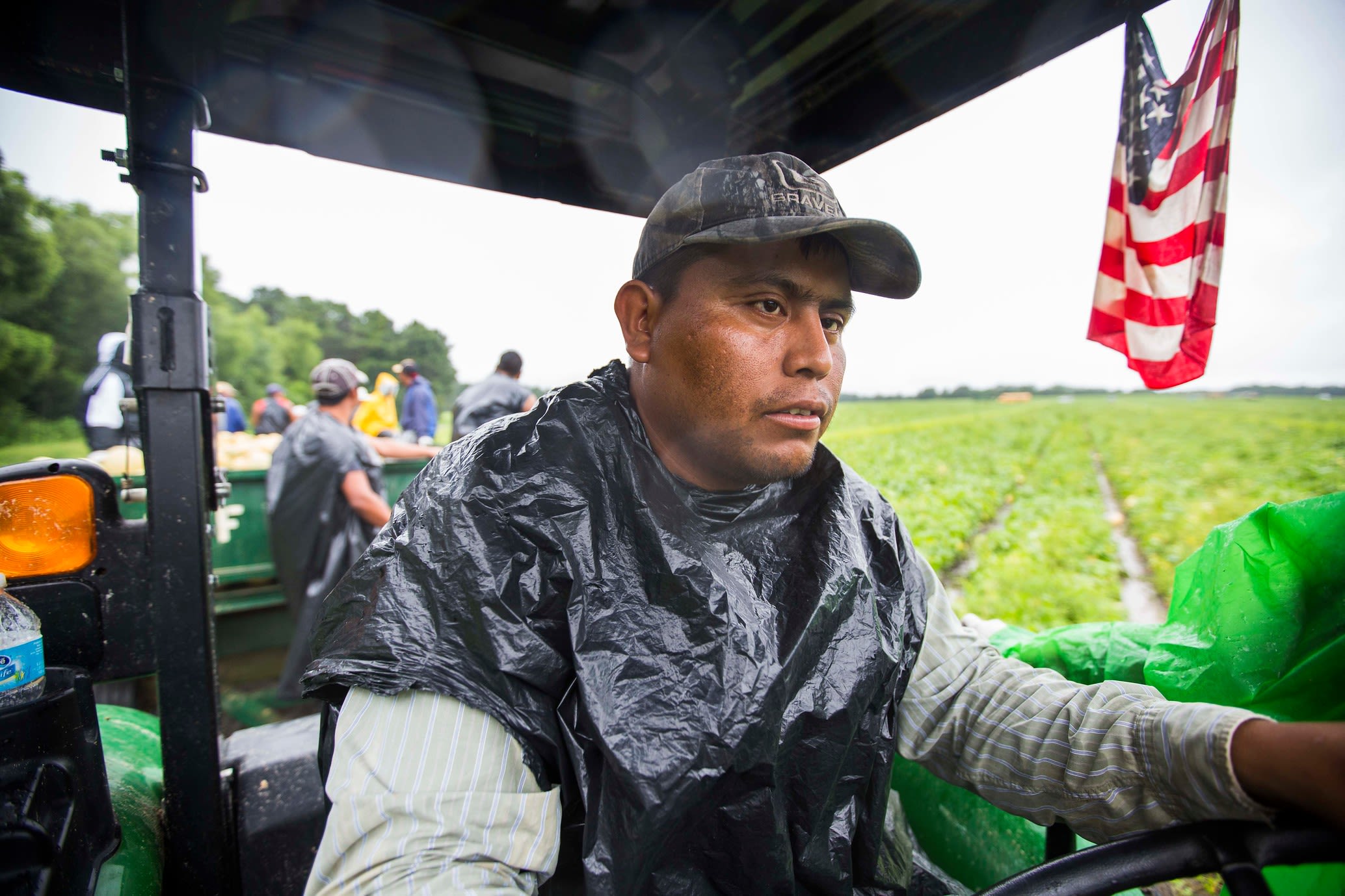 A farm worker rides in his farm equipment