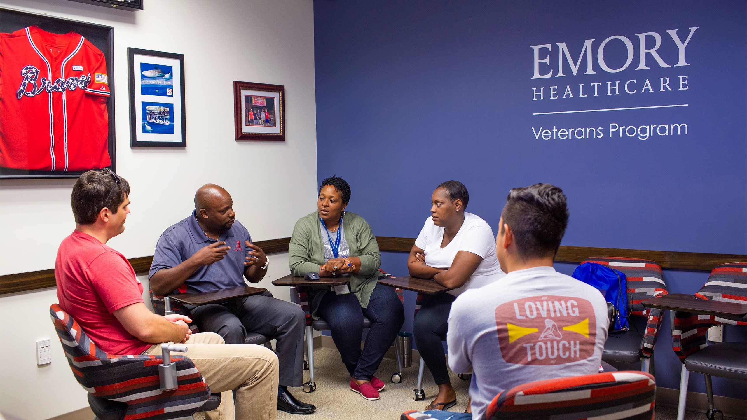 Five people sit in chairs in a circle having a discussion at the Emory Healthcare Veterans Program.