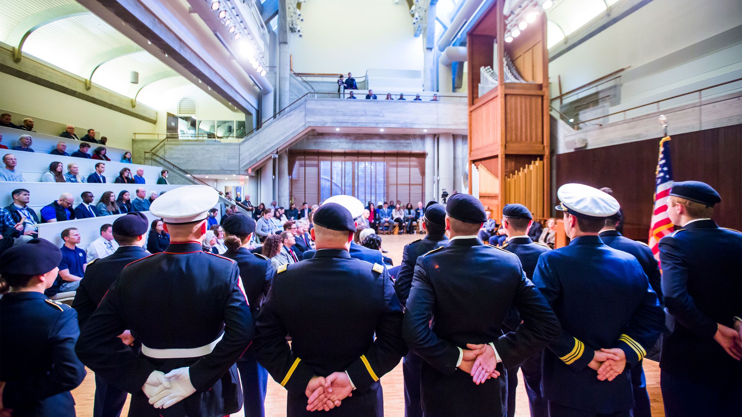 An honor guard in uniform stands with backs to the camera. You can see the full audience in Cannon Chapel.