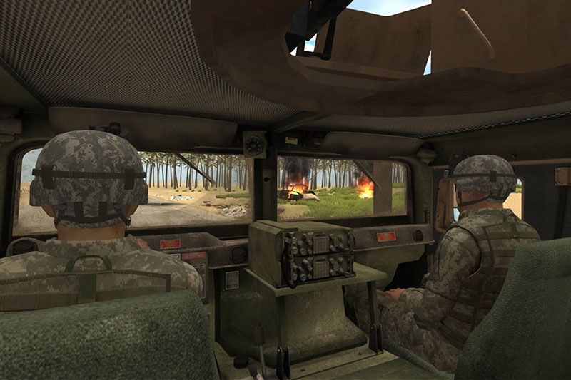 A view from the backseat of a military truck. Fires are visible through the windshield.