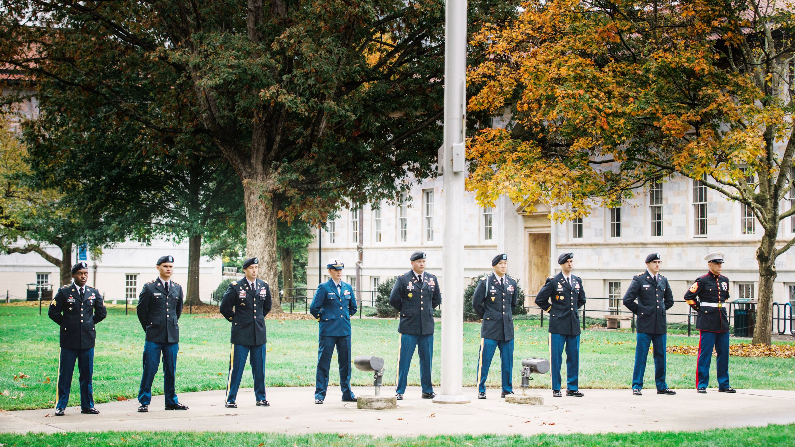 Men and women in uniform stand at attention by the Emory flag pole during the annual Veterans Day ceremony.