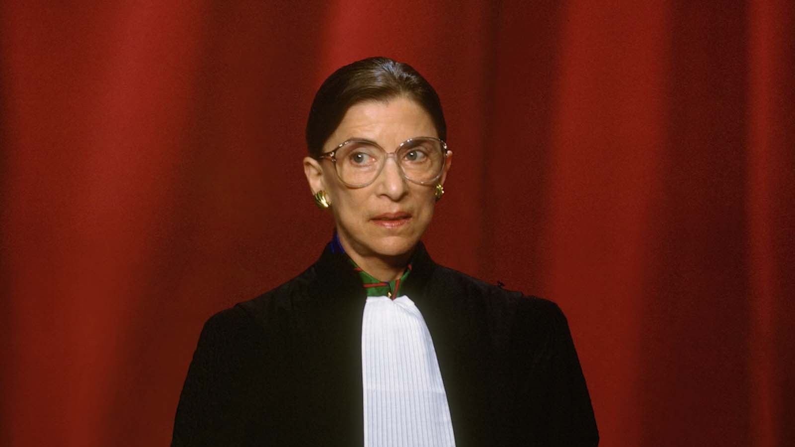 Ruth Bader Ginsberg in front of a red background.