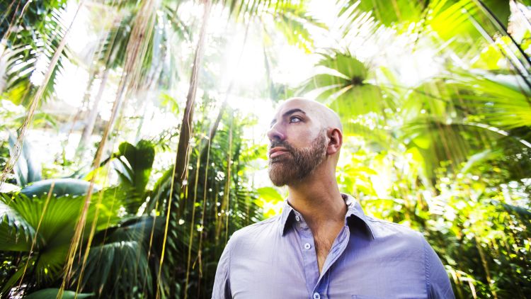Emory College professor Thomas Gillespie poses in front of many tropical plants