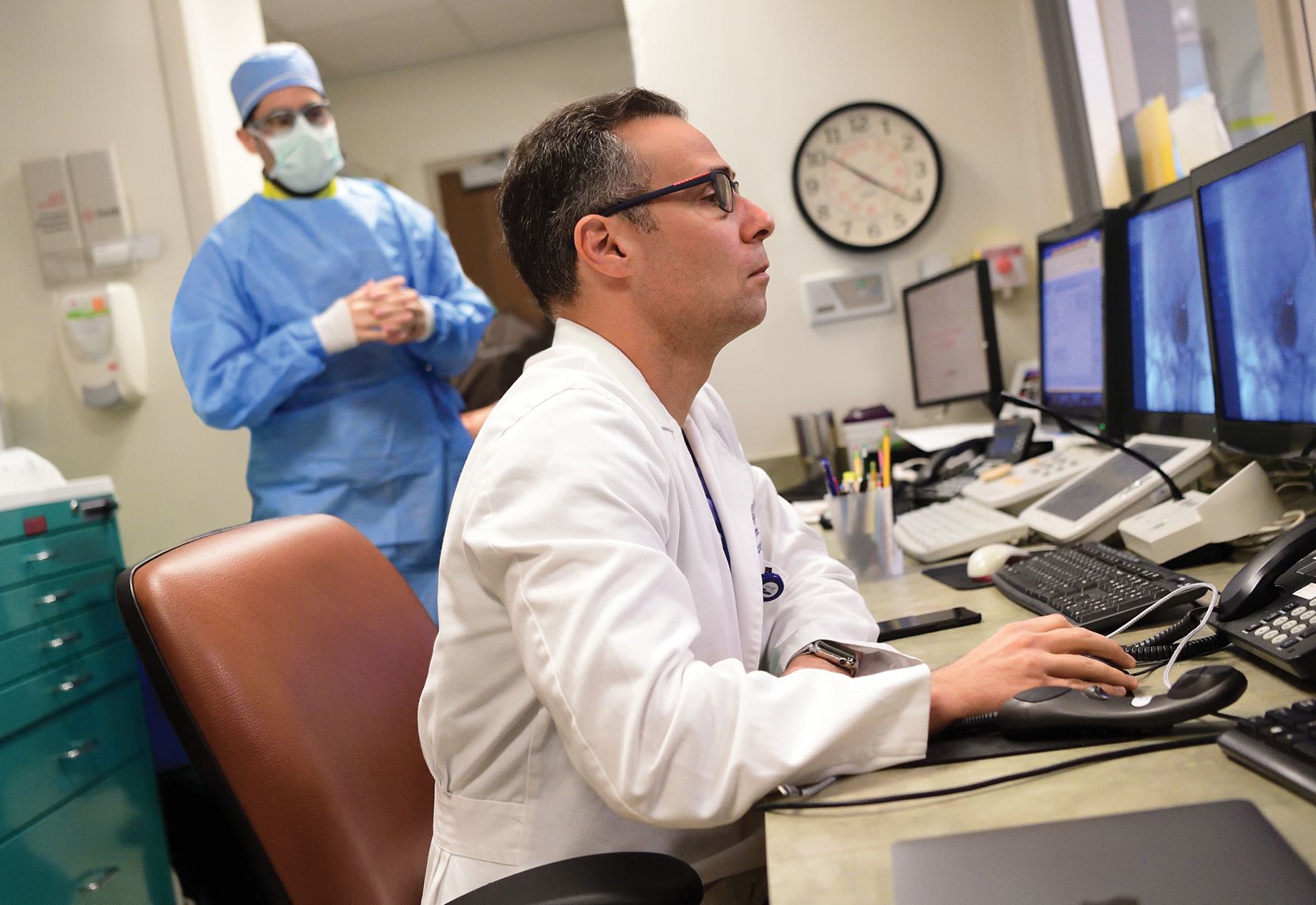 image of neruologist Raul Nogueira looking at a computer screen with a scan image of brain