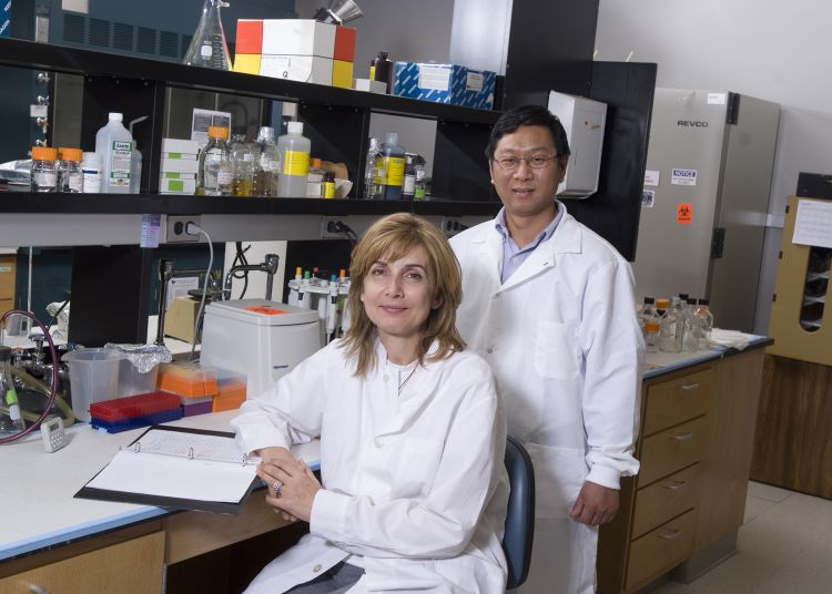 Researchers Ioanna Skountzou and Chinglai Yang in white coats in a research lab. 