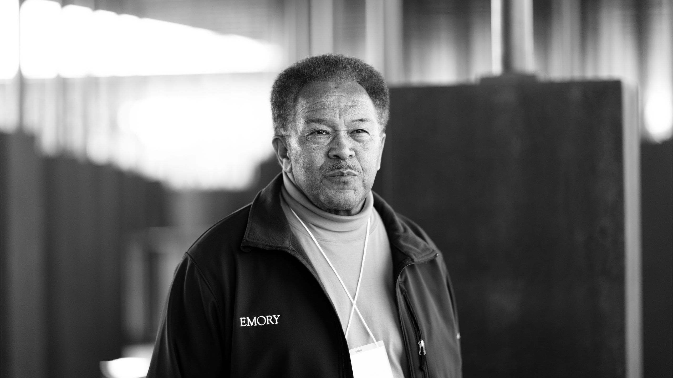 A portrait shows Robert Franklin wearing an Emory jacket and standing in the National Memorial for Peace and Justice.