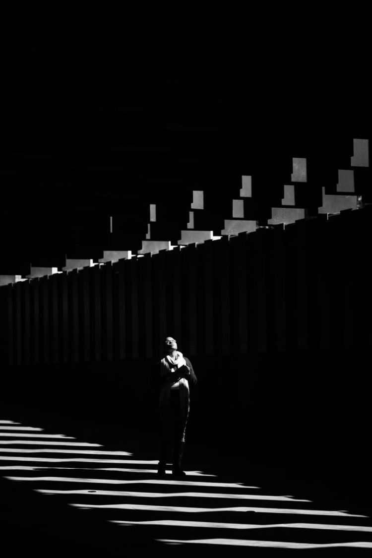 A participant in the Candler trip stands among the columns at the National Memorial for Peace and Justice, surrounded by columns and shadows.