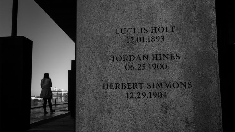 An up-close photo of one of the concrete columns in the memorial bears three names with their dates of death: Lucius Holt (12.01.1893), Jordan Hines (06.25.1900) and Herbert Simmons (12.29.1904)