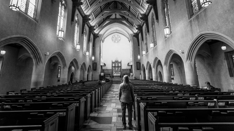 A student stands in the aisle while others sit in the pews of the First United Methodist Church.