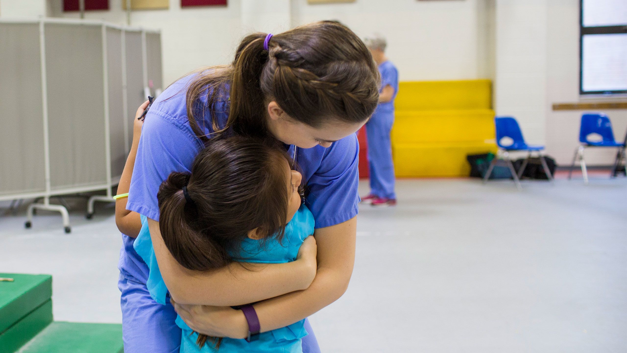 An Emory student volunteer hugs a young girl at a clinic for migrant farm workers and their families.