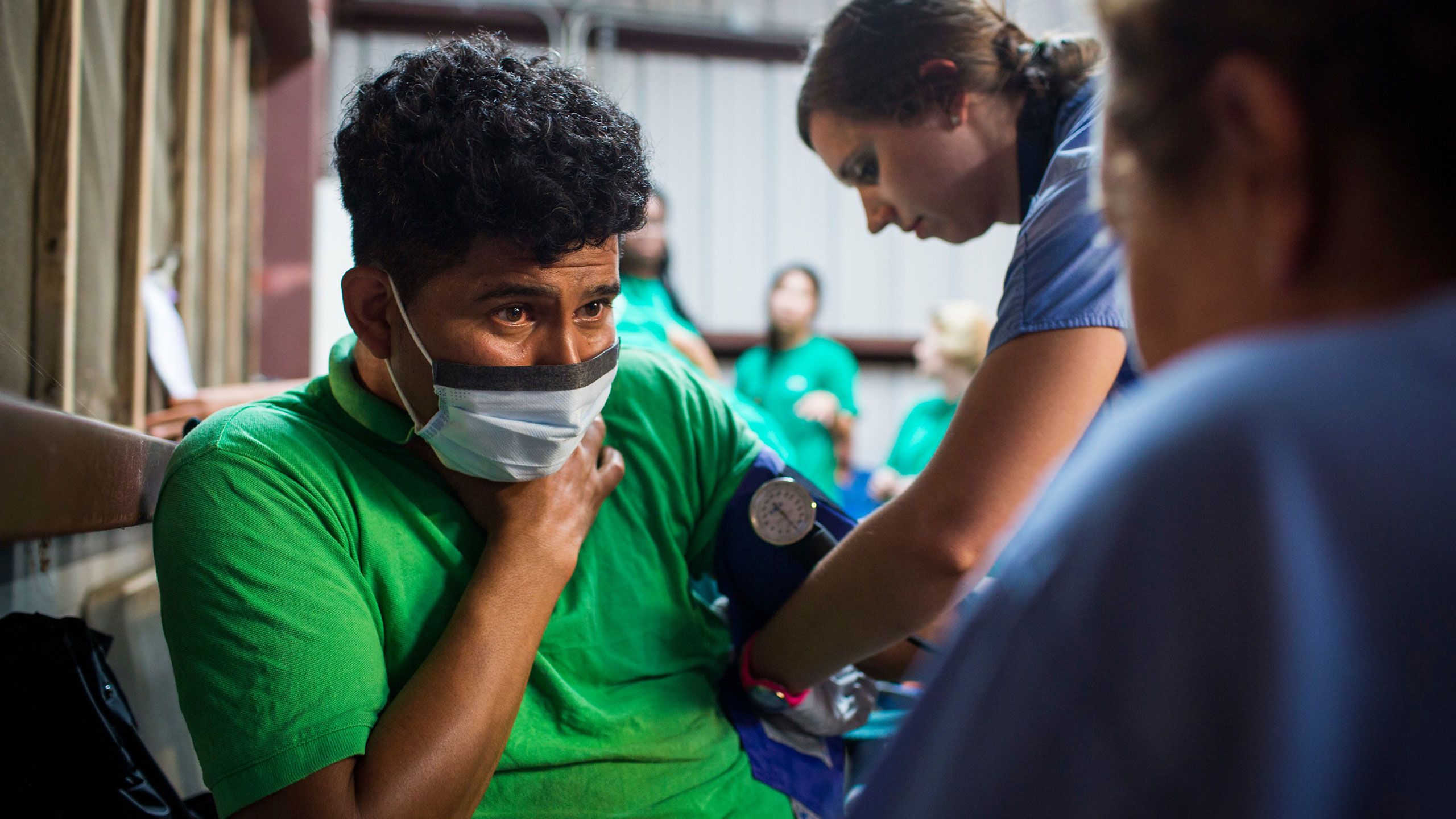 Two Emory students help a patient wearing a face mask