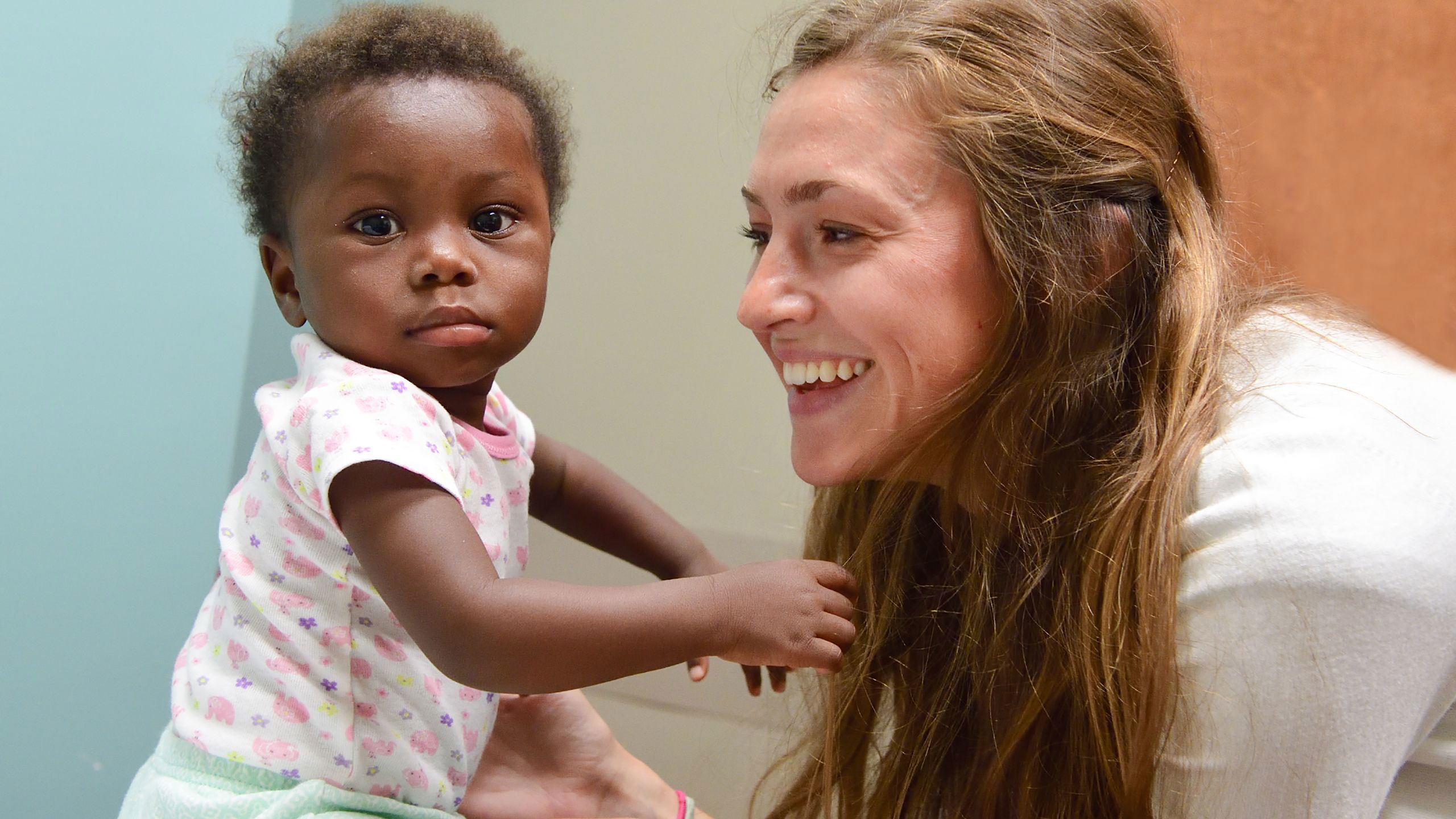 One-year-old Sara looks quizzically at the camera as Justine Broecker smiles at her