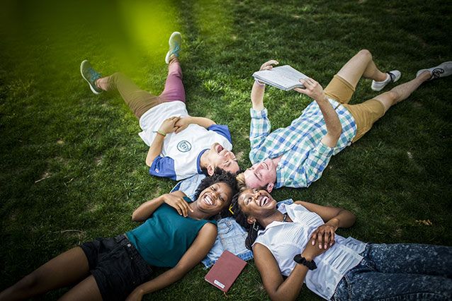 Four Emory undergraduate students lay on the lush grass on the Emory Quad