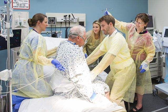 Four medical professionals assist an older patient